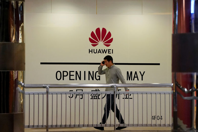 © Reuters. Un hombre habla por su móvil mientras camina por delante de una tienda de Huawei a punto de abrir en un centro comercial de Shanghái