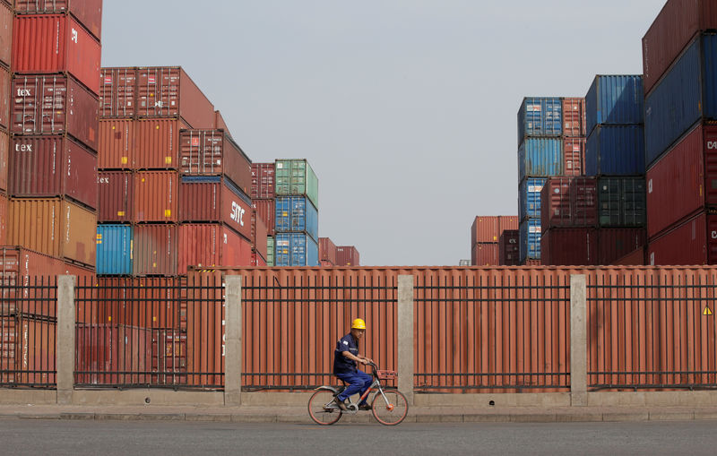 © Reuters. A worker cycles past containers outside a logistics center near Tianjin Port