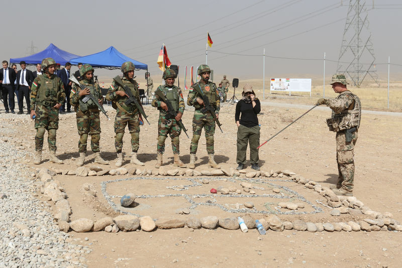 © Reuters. A soldier of the German Bundeswehr (R) instructs soldiers of the Kurdish Peshmerga during a visit by German Minister of Defense Ursula von der Leyen at the educational centre Banslawa near Erbil