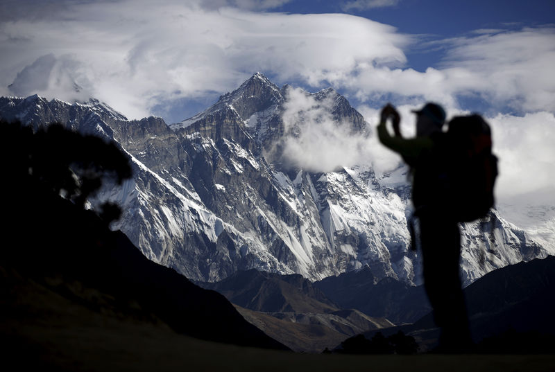 © Reuters. FILE PHOTO: A tourist is silhouetted as he takes pictures of Mount Nuptse as Mount Everest is covered with clouds in Solukhumbu district, also known as the Everest region