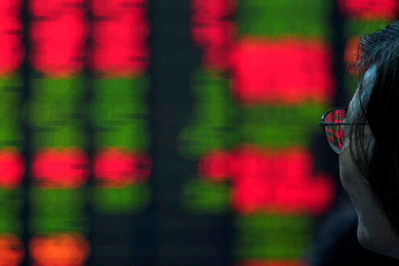 © Reuters. FILE PHOTO: An investor looks at an electronic board showing stock information at a brokerage house in Shanghai