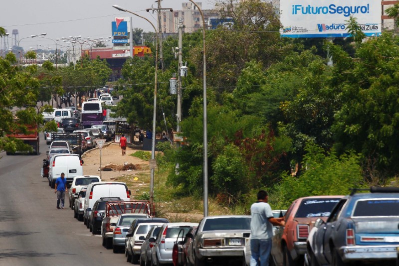 © Reuters. Personas y sus vehículos esperan en una fila para repostar combustible en una gasolinera de la petrolera estatal PDVSA en Maracaibo.
