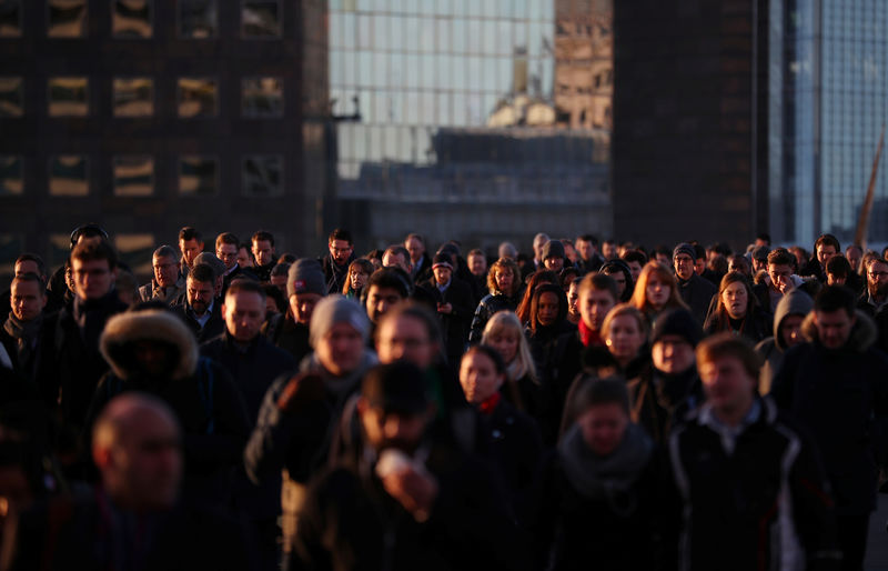 © Reuters. Commuters walk across London Bridge at sunrise in London