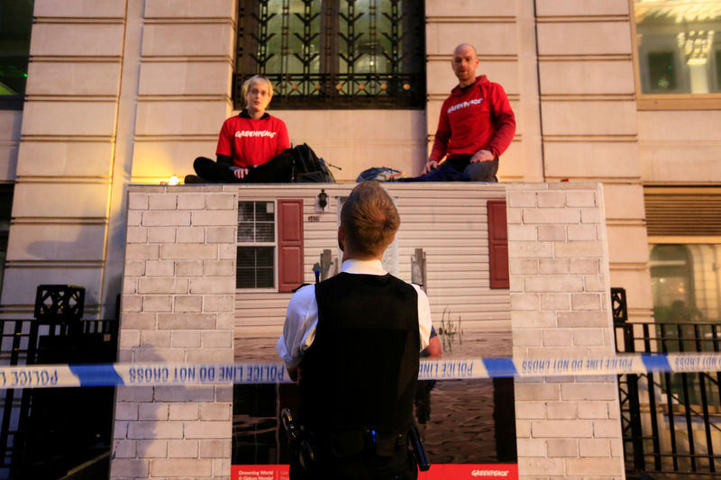 © Reuters. Policial britânico observa ativistas do Greenpeace em barricada na sede da BP