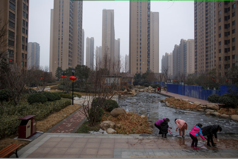 © Reuters. People play with ice floats at a pond in the compound of a apartment complex in Zhengzhou