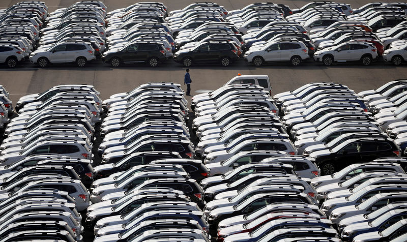© Reuters. FILE PHOTO: A worker is seen among newly manufactured cars awaiting export at the port in Yokohama