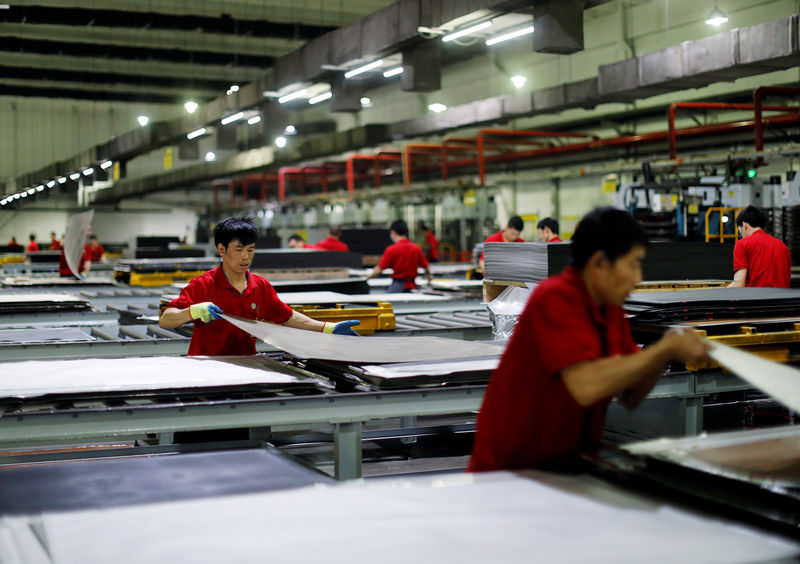 © Reuters. Employees work on a PVC plastic flooring production line in Zhangjiagang Yihua Rundong New Material Co., Ltd in Zhangjiagang