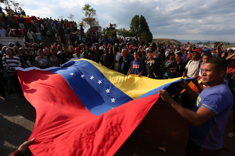 © Reuters. Venezuelanos seguram bandeira do país durante manifestação de apoio ao governo de Nicolás Maduro na fronteira com o Brasil, em Pacaraima, em Roraima