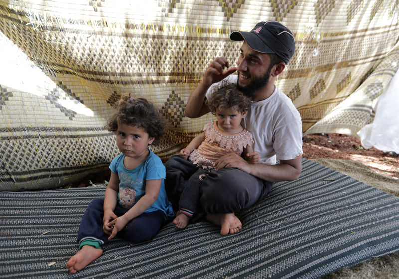 © Reuters. عائلة سورية تجتاز الأراضي الزراعية فرارا من هجمات إدلب