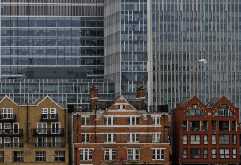 © Reuters. FILE PHOTO: Apartment buildings are backdropped by skyscrapers of banks at Canary Wharf in London