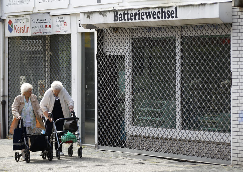 © Reuters. Elderly women walk past an empty shop in Herten