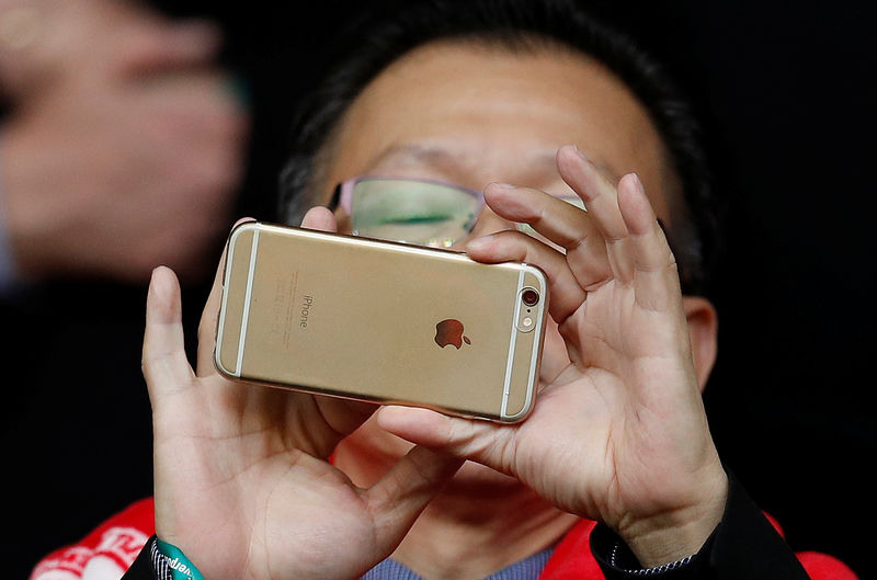 © Reuters. FILE PHOTO: A man uses an Apple iPhone to take photographs before the Liverpool versus Tottenham Hotspur soccer match at  Anfield in Liverpool northern England.
