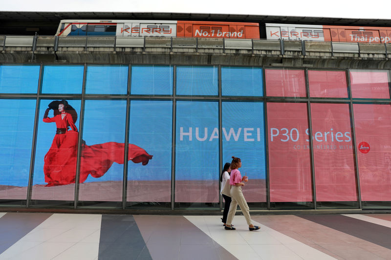 © Reuters. FILE PHOTO: Women walk past a Huawei P30 advertising LED board at a shopping centre in Bangkok