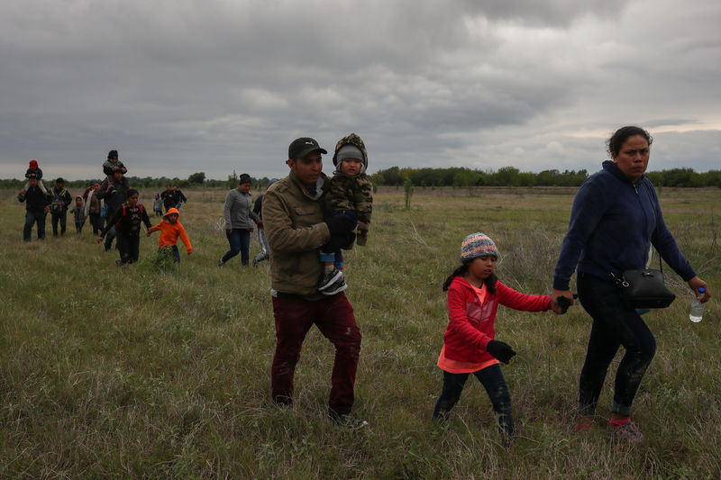 © Reuters. Migrant families seeking asylum walk through field after illegally crossing into the U.S. from Mexico in Penitas, Texas