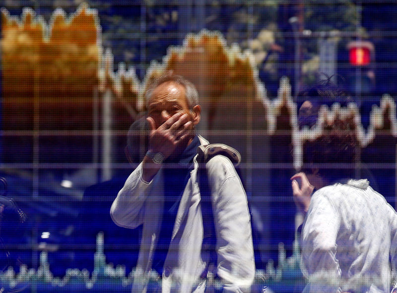 © Reuters. FILE PHOTO: A man is reflected in an electronic board showing the graph of the recent fluctuations of the TOPIX outside a brokerage in Tokyo