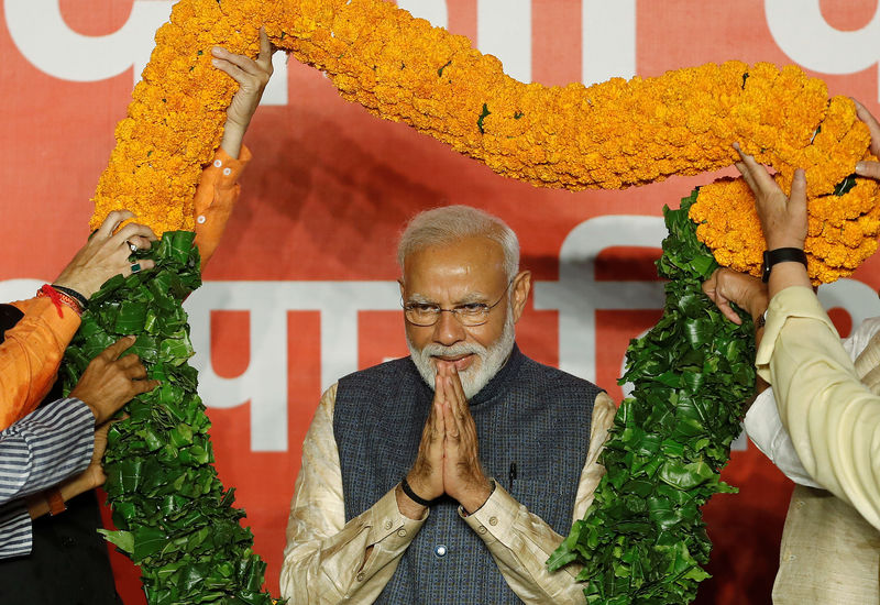 © Reuters. Indian Prime Minister Narendra Modi gestures as he is presented with a garland by Bharatiya Janata Party (BJP) leaders after the election results in New Delhi