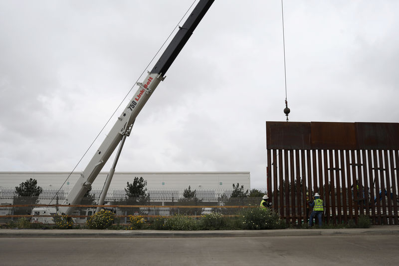 © Reuters. Workers replace a section of the border fence between U.S. and Mexico, as seen from Tijuana