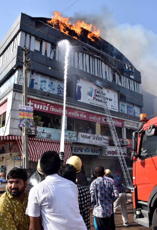 © Reuters. FILE PHOTO: Firefighters douse a fire that broke out in a four-story commercial building in Surat