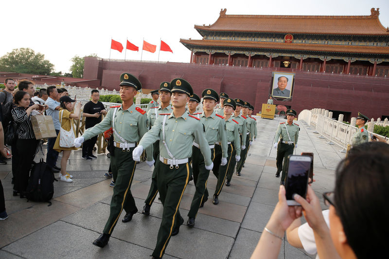 © Reuters. La gente toma fotos de oficiales paramilitares marchando en formación en la Plaza de Tiananmén en Beijing, China