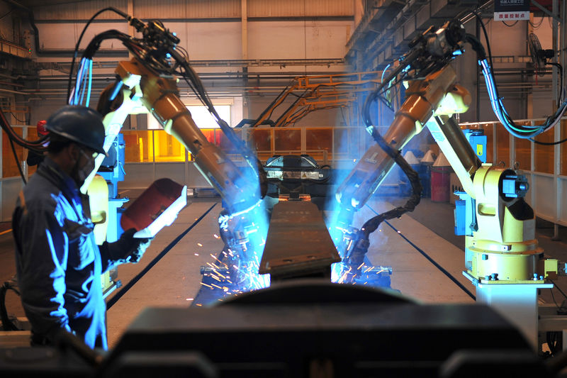 © Reuters. FILE PHOTO: Worker stands next to robotic arms welding pump truck part at a factory of the Foton Loxa Heavy Machinery Co in Zhangjiakou, Hebei