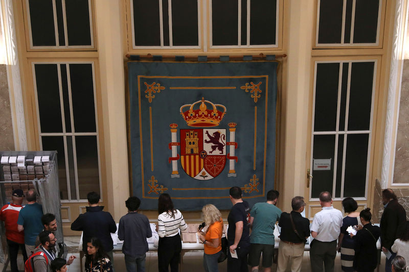 © Reuters. El escudo de España se exhibe en un colegio electoral donde la gente espera para emitir su voto