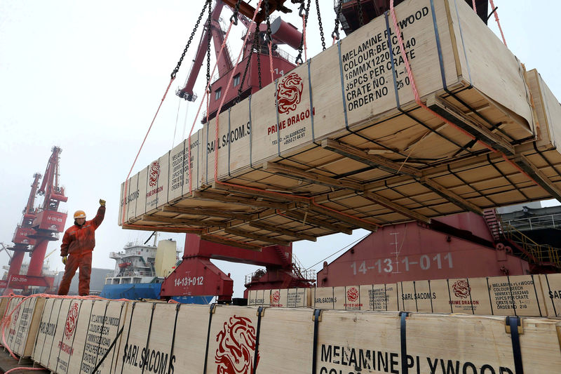 © Reuters. FILE PHOTO: Worker gestures as a crane lifts goods for export onto a cargo vessel at a port in Lianyungang, Jiangsu