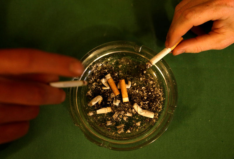 © Reuters. Men tap ashes off their cigarettes into an ashtray in a pub in Prague