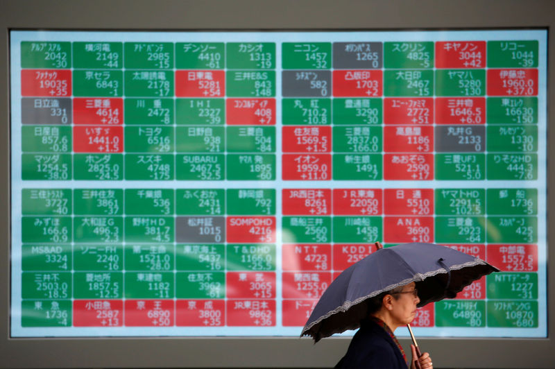 © Reuters. A passerby walks past in front of a stock quotation board outside a brokerage in Tokyo