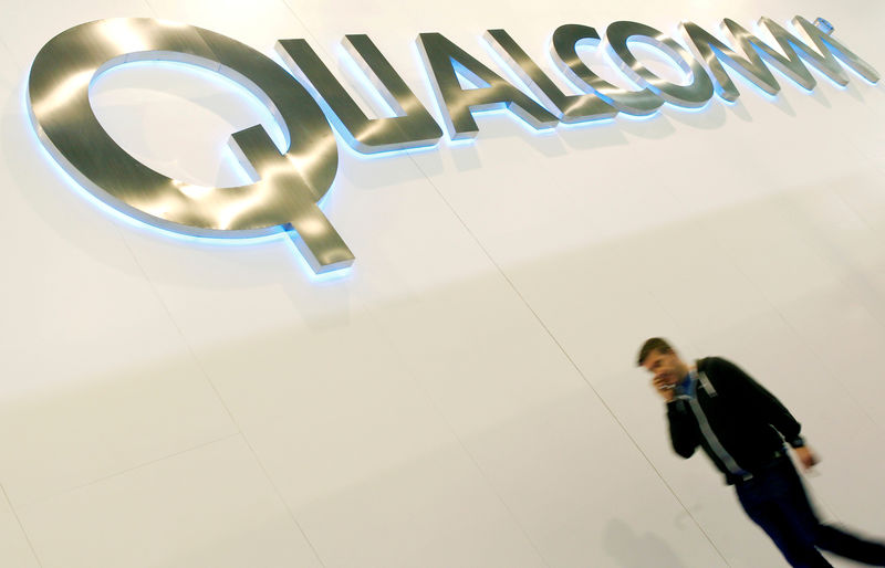 © Reuters. FILE PHOTO: A man walks past a Qualcomm advertising logo at the Mobile World Congress at Barcelona