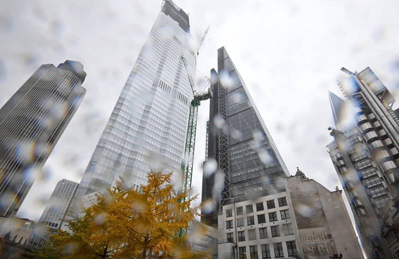 © Reuters. A tree covered in autumn foliage is seen with office skyscrapers around it during rainfall in the City of London, Britain