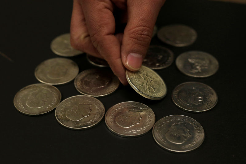 © Reuters. A man arranges Mexican 5 Pesos Hidalgo silver coins at currency exchange shop in Ciudad Juarez