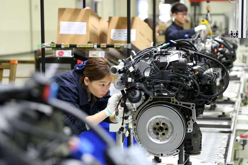 © Reuters. FILE PHOTO: Employees work on the production line at a factory of automotive engine manufacturer Power Xinchen in Mianyang