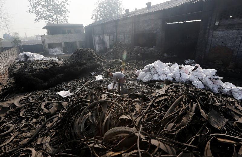 © Reuters. A boy scouts for scrap items amidst a pile of used tyres at a pyrolysis unit in Jokhabad