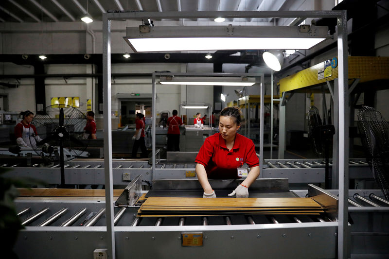 © Reuters. FILE PHOTO: Employees work on a vinyl flooring production line in Zhangjiagang Yihua Rundong New Material Co., Ltd in Zhangjiagang