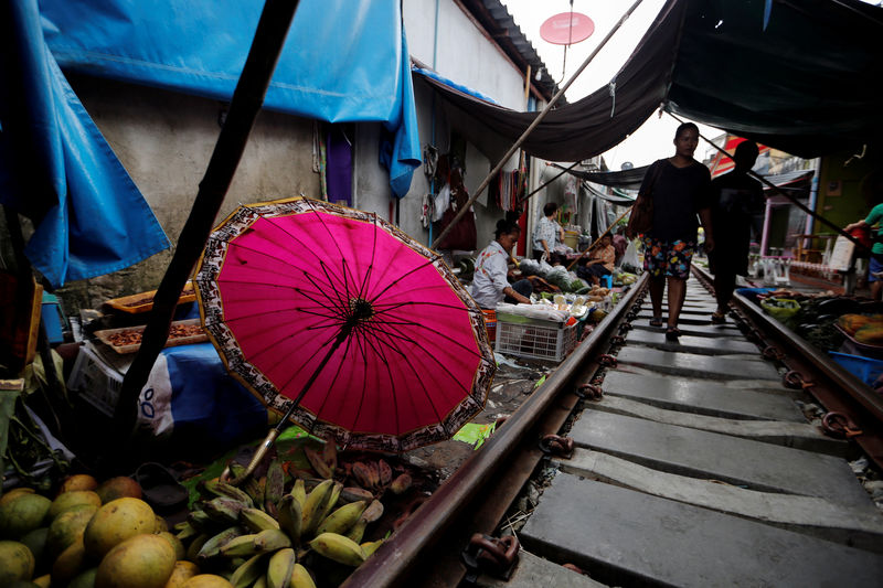 © Reuters. A woman walks at the Maeklong market next to the train tracks, on the outskirts of Bangkok