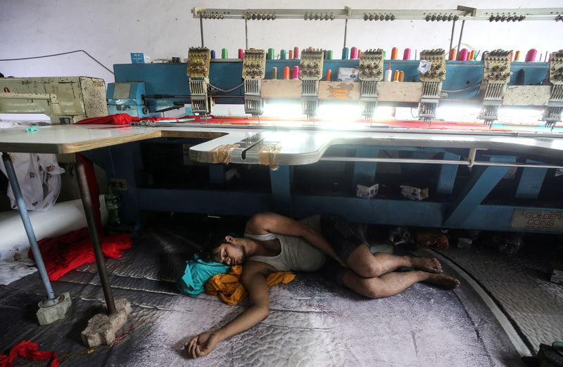 © Reuters. A worker sleeps underneath an embroidery machine at a workshop in Mumbai