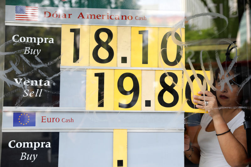 © Reuters. An employee changes the board with the exchange rate for Mexican Peso and U.S. Dollar at a CI Bank branch in Mexico City