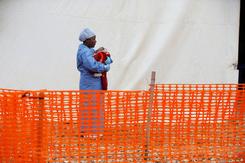 © Reuters. Rachel Kahindo, superviviente del ébola que trabaja como cuidadora de bebés diagnosticados con la enfermedad, sostiene en brazos a un bebé fuera de la zona roja en el centro de tratamiento de ébola en Butembo