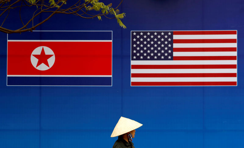© Reuters. Una persona pasa junto a una pancarta que muestra las banderas de Corea del Norte y Estados Unidos antes de la cumbre bilateral entre ambos países en Hanoi