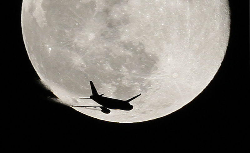 © Reuters. An airplane is silhouetted against a full moon in the sky over London