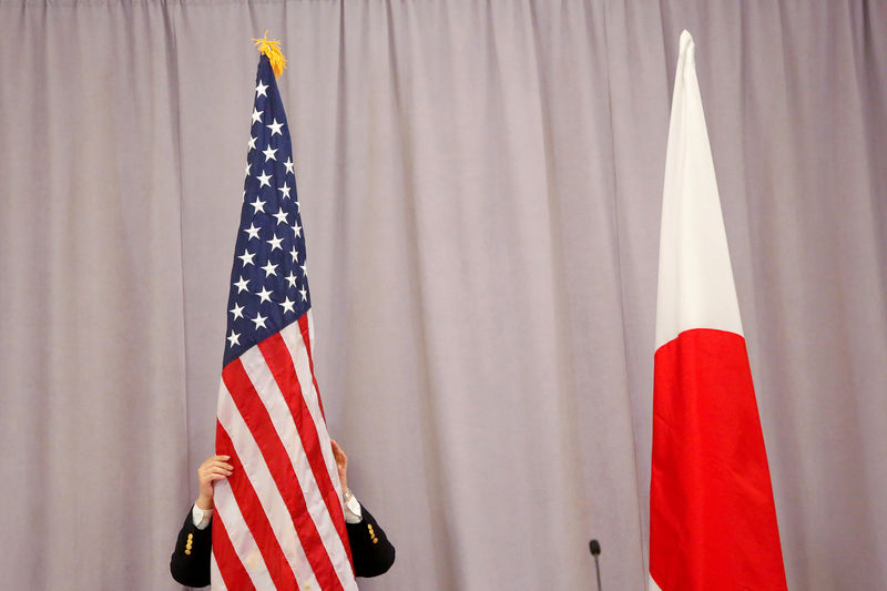 © Reuters. A worker adjusts the U.S. flag before Japanese Prime Minister Shinzo Abe addresses media following a meeting with President-elect Donald Trump in Manhattan, New York, U.S.