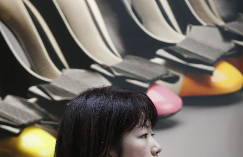 © Reuters. Una mujer pasa junto a un anuncio de zapatos de tacón en una tienda de lujo en Tokio