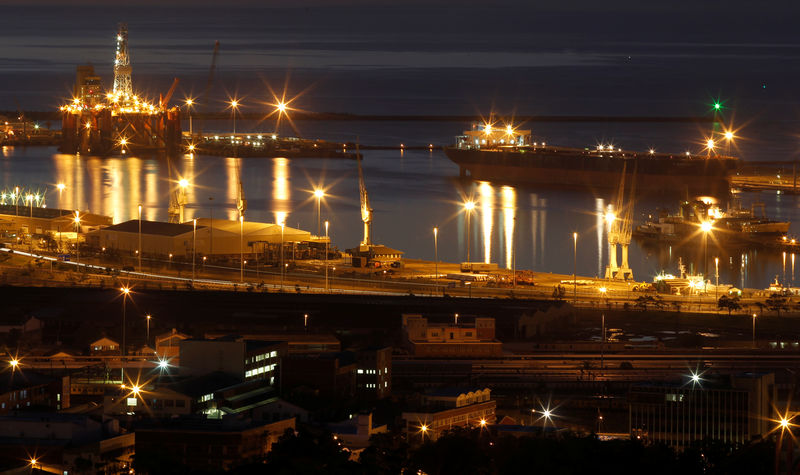 © Reuters. An oil rig lights up Cape Town harbour as the sun sets