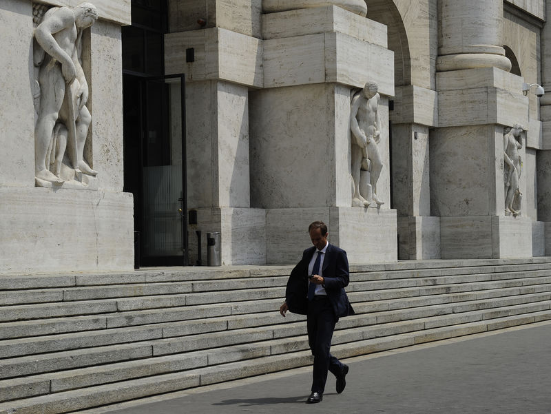 © Reuters. Un uomo passeggia davanti alla Borsa di Milano