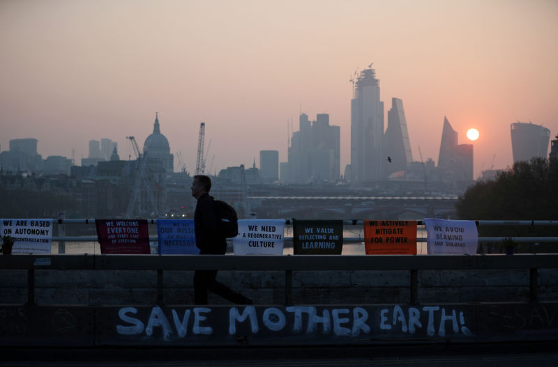 © Reuters. FILE PHOTO: A commuter walks along Waterloo Bridge, which is being blocked by climate change activists, during the Extinction Rebellion protest in London
