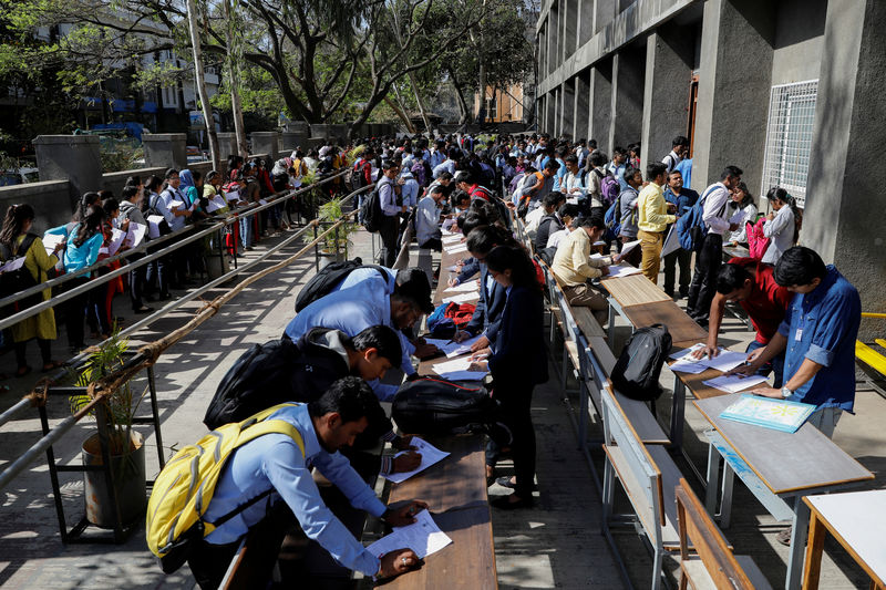 © Reuters. FILE PHOTO: Job seekers fill up forms as others line up for registration during a job fair in Chinchwad