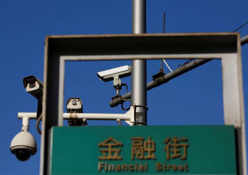 © Reuters. FILE PHOTO: Security cameras are seen behind a road sign of Financial Street near the headquarters of the People's Bank of China in Beijing