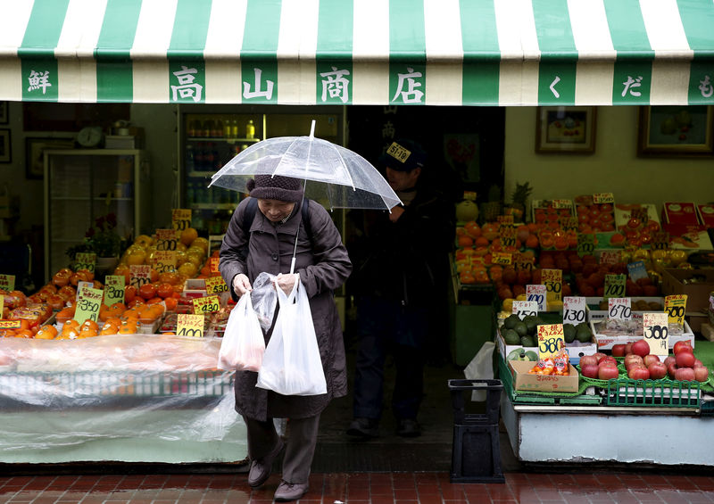 © Reuters. FILE PHOTO: A shopper holding plastic bags walks out from a greengrocer's at Tokyo's Sugamo district, an area popular with the Japanese elderly, in Tokyo
