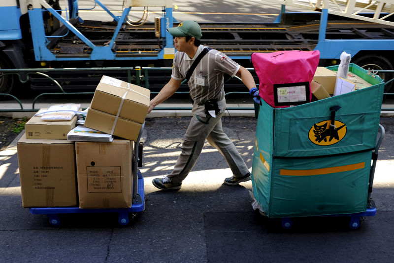 © Reuters. FILE PHOTO: A delivery man moves carts with parcels in Tokyo