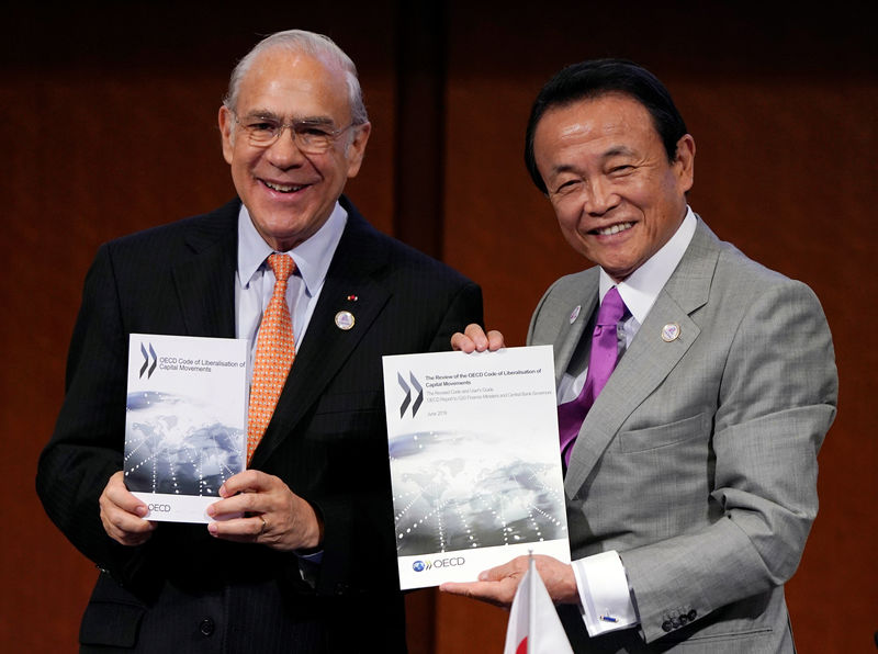 © Reuters. OECD Secretary-General Angel Gurria (L) and Japan's Finance Minister Taro Aso pose holding the revised OECD Code of Liberalization of Capital Movements during the G20 finance ministers and central bank governors meeting in Fukuoka